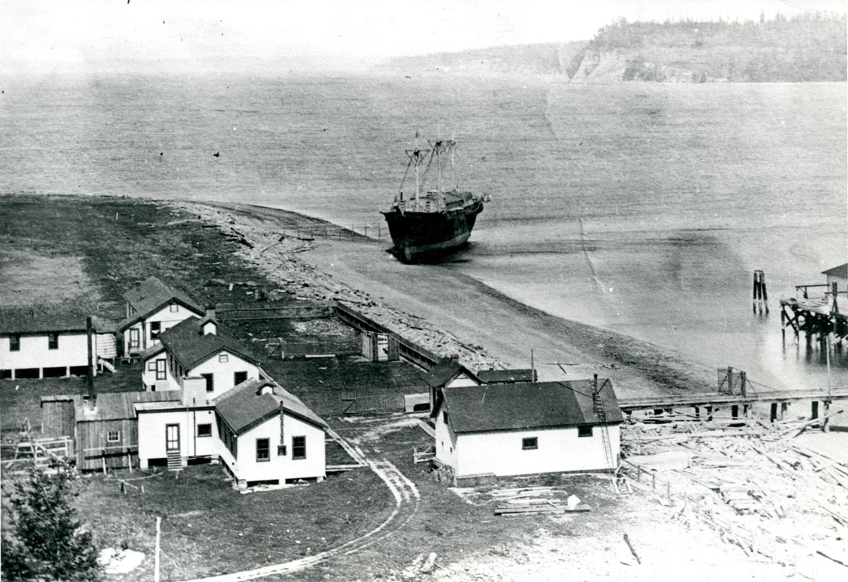 historical image of buildings on a coastline with a boat just offshore