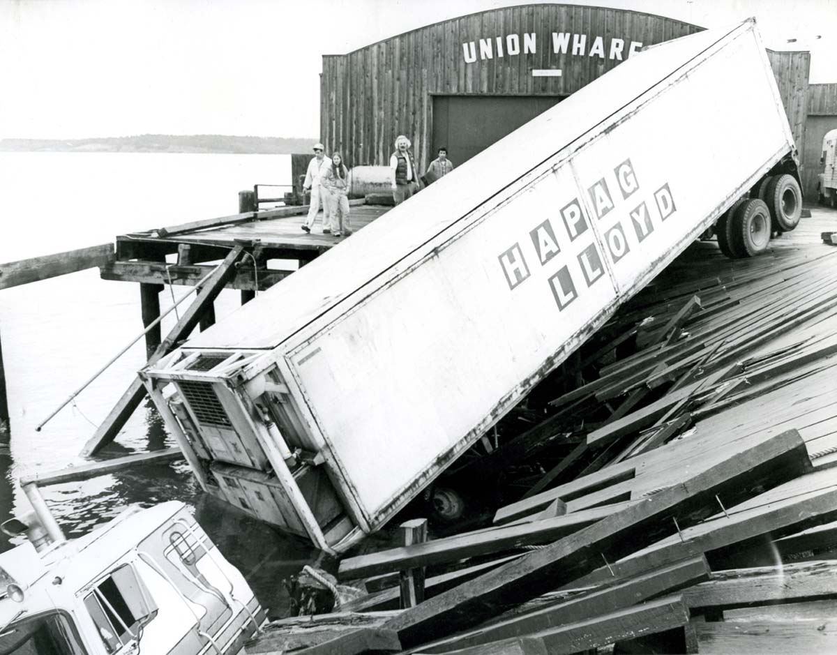 historical image of a crashed semi truck trailer resting on a dock